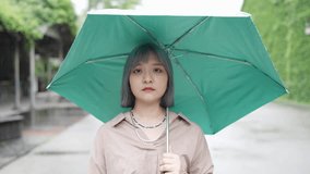 A young Taiwanese woman making various expressions with an umbrella at an artistic building in the Huashan 1914 Cultural and Creative Park in Taipei.
