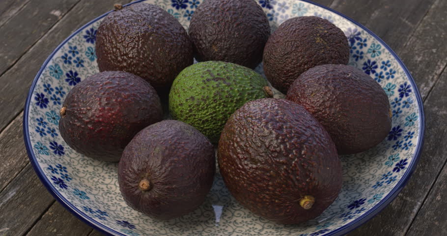 Whole hass avocados (Persea americana) on a plate. Table spin.
