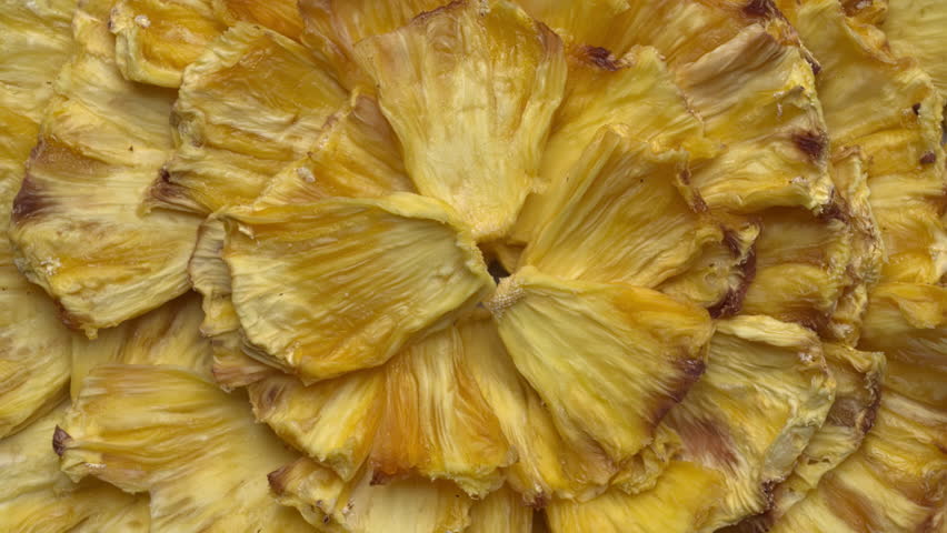 Background texture formed from home-dried pineapple slices. Table spin.
