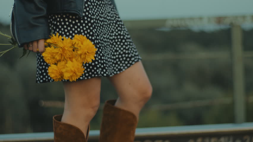 A young woman with yellow flowers dances at the evening sky.