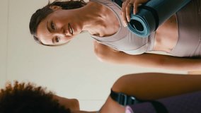 Vertical video of two female friends talking and catching up at gym or yoga studio for exercise - shot in slow motion