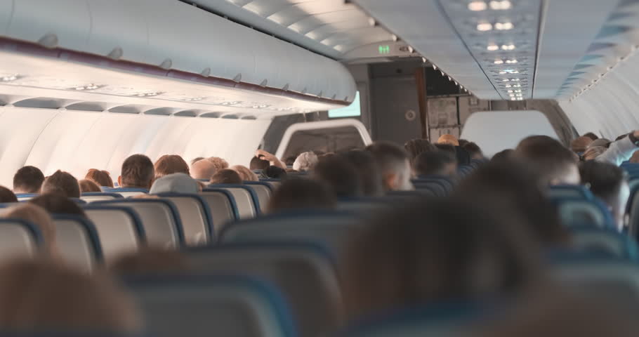 Passengers sitting on aircraft inside, back view. Unrecognizable people flying on airplane. Passenger commercial air transportation by economy class. Low cost, economy cabin. Row seat with people Royalty-Free Stock Footage #1110859993