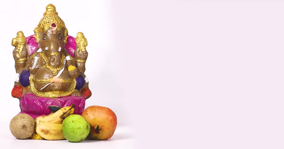 Ganesha Chaturthi festival is celebrated with Ganesha sculpture of Hindu god Ganesha and fruits on white background by sprinkling flowers on Ganesha sculpture. Royalty-Free Stock Footage #1110861139