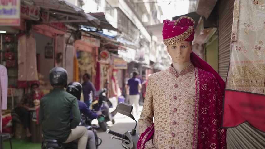 A male mannequin dressed up in a Hindu Indian traditional or ethnic wedding attire is kept outside the cloths store or shop located in a busy bazaar lane or market street | Shutterstock HD Video #1110863477
