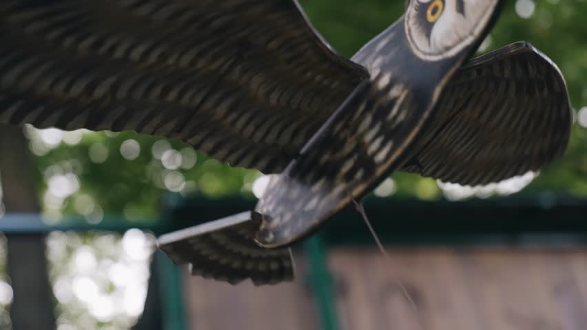 A wooden figure of a bird moves and flaps its wings with the help of strings. Funny toy