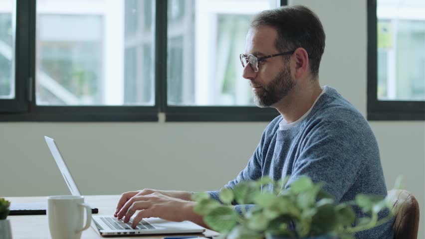 Businessman sitting at desk working on laptop - Powered by Shutterstock - Get 15% off with code: PIKWIZARD15