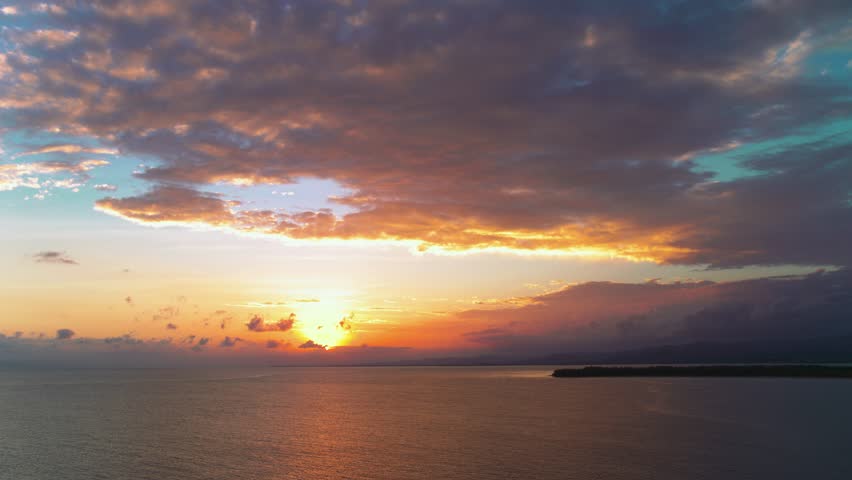Orange sunset over the sea on a tropical summer evening. Sea waves with the reflection of the setting sun. Rippling water with sun rays. Deep blue ocean under an orange sky. Twilight over the sea.