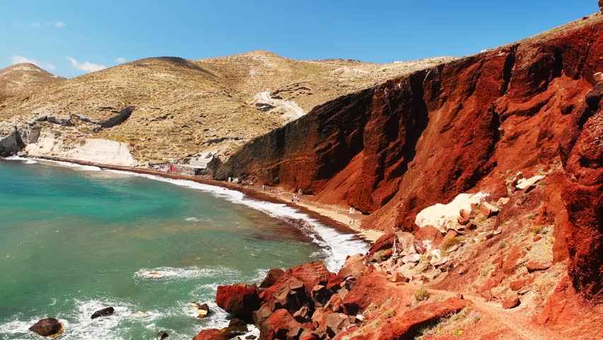 Red beach in Santorini island, Greece. Red volcanic cliffs and the blue sea, black sand on the beach. Beautiful summer landscape. Zoom out
