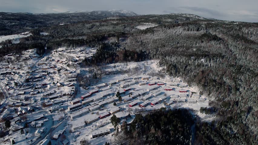 Trondheim, Norway, Aerial drone forward descending shot over city houses covered with thick white snow on a cold winter day.