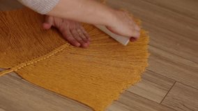 a girl weaves macrame in the form of a large leaf in a bright room. women's hands weave macrame. macrame in the video of a large sheet hanging on the wall.