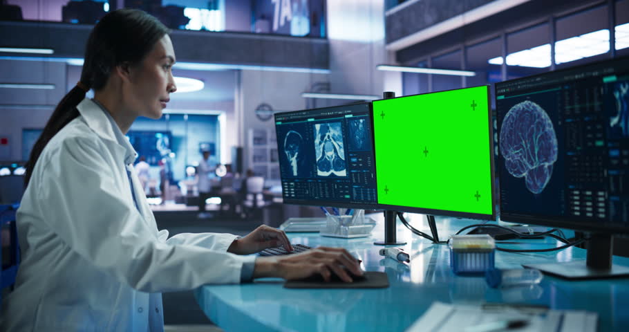 Hospital Research Laboratory: Asian Female Medical Scientist Using Computer Green Screen Chromakey On Display. Neurologist Analysing CT Scans, Finding Treatment for Patients With Brain Damage.