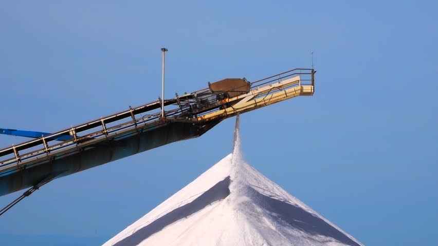 The newly produced salt from the salt pans in Aigues Mortes, France, is transported on a conveyor belt on the top of a salt pile, a so-called camel or pyramid - closeup, steadicam