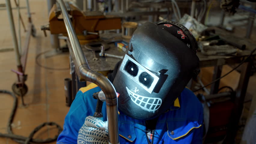 Factory Man Welding A Metal Detail In Funny Protective Mask. Production Facility. Welding Process At Industrial Plant. Welding Requires Professional Skills. Horror Film. Bright Blue Light. | Shutterstock HD Video #1110882087