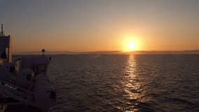 This video captures the first light of day breaking over the horizon, viewed from the deck of a ferry. As the sun rises, its rays dance across the gentle waves, creating a path of shimmering gold.