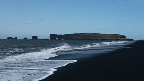 Beauty of Iceland's Black Sand Beach. Rugged landscapes and volcanic serenity. Dyrhólaey promontory in the distance. White waves roll out over the black volcanic sand. Reynisfjara beach. - Powered by Shutterstock - Get 15% off with code: PIKWIZARD15