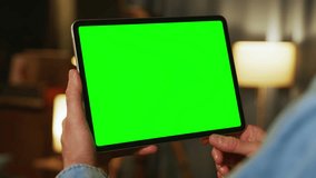 Hands man holding tapping on tablet computer with horizontal green screen. Mock up. In the evening