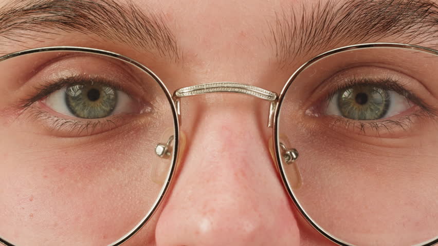 Young attractive brunette woman with curly hair in a bun wearing glasess close-up, white background. Portrait