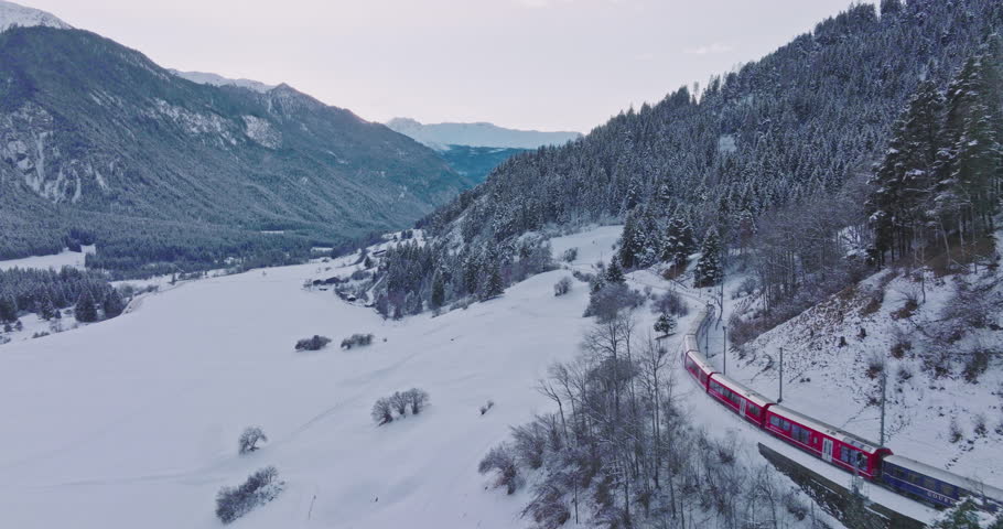 Landwasser Viaduct world heritage sight with luxury Glacier and Bernina express in Swiss Alps snow winter scenery. Aerial Drone shot red train passing through famous mountain in Filisur, Switzerland. | Shutterstock HD Video #1110899737