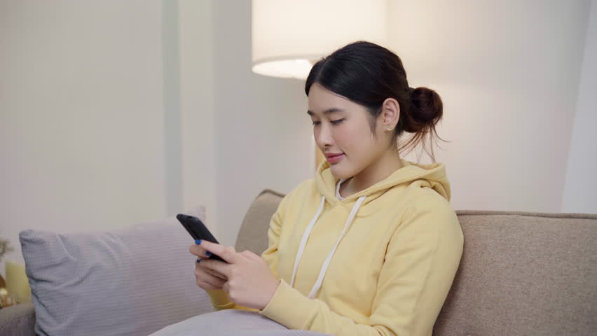 Asian girl looking at mobile phone and smiling
