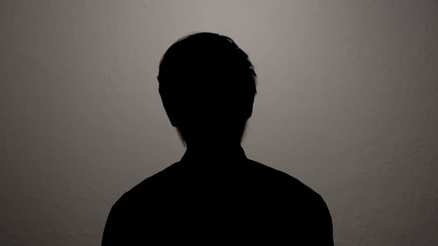 Silhouette of man hiding identity while giving anonymous interview on camera.