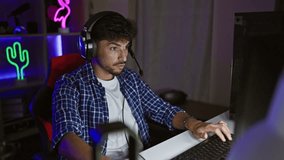 Exciting stream reveal, young arab man taking off headphones, pointing at camera during night game stream in his gaming room