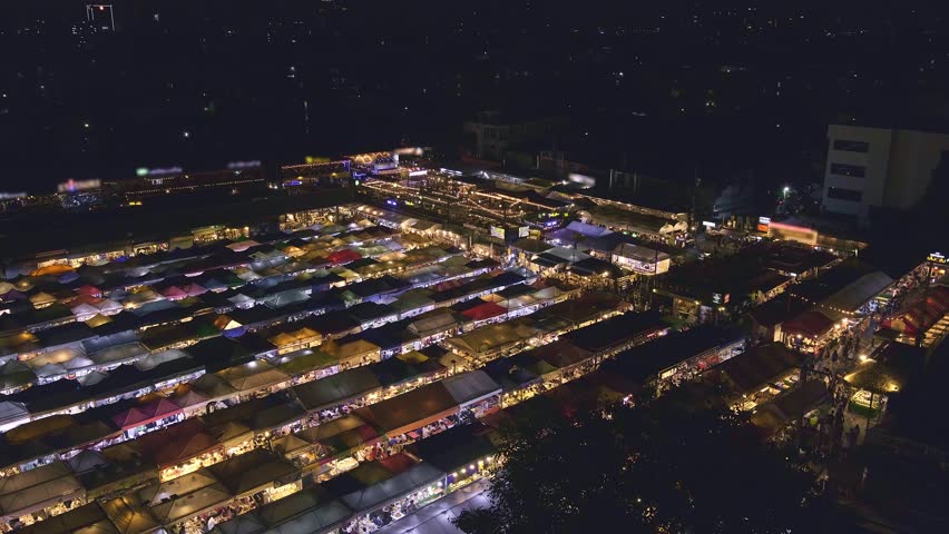 Panning over rows of colorful outdoor market tents and food stalls at night. Fairs, marketplaces, small businesses, shopping and dining outdoors, Asian markets, local traditions, tourist traps or