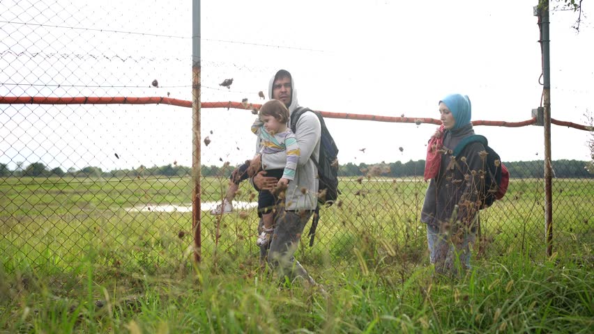 migrant family walk along fence border problem of undocumented persons Royalty-Free Stock Footage #1110908527