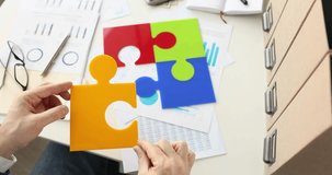 Businessman puts color puzzles on table in office. Drawing up business project concept