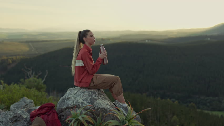 Hiking, view of mountain and woman drinking water, relax on outdoor adventure and freedom in nature. Trekking, calm rock climbing and hiker girl sitting with bottle, backpack and motivation to travel
