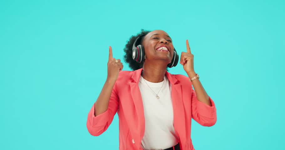 Music, dancing and black woman with headphones to listen in studio isolated on a blue background mockup space. Radio, streaming and happy person hearing podcast, sound or audio for moving with energy Royalty-Free Stock Footage #1110912169