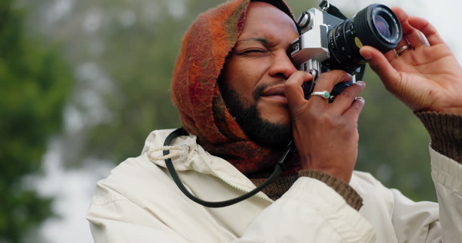 Black man in nature, smile and camera with camping on morning winter adventure, peace and calm. Relax, freedom and photography, camper in forest for hiking in trees and travel holiday in woods.