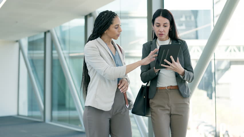 Business, women walking and talking with tablet in office, workplace or employees networking for collaboration. Professional, advice or feedback on project, report or information on mobile app