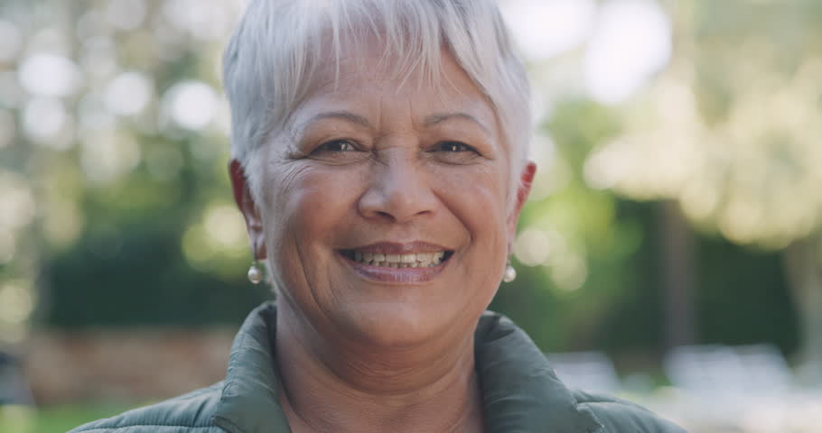 Happy, smiling and beautiful senior woman showing off her perfect teeth with bokeh. Closeup, casual and aged lady with lovely skin and cosmetics. Candid elderly caucasian laughing as she takes a walk