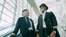 Pilots, escalator and people at airport for travel, talking and conversation in low angle. Mature, captain and first officer at stairs for communication, speaking or discussion at lobby with suitcase - Powered by Shutterstock - Get 15% off with code: PIKWIZARD15
