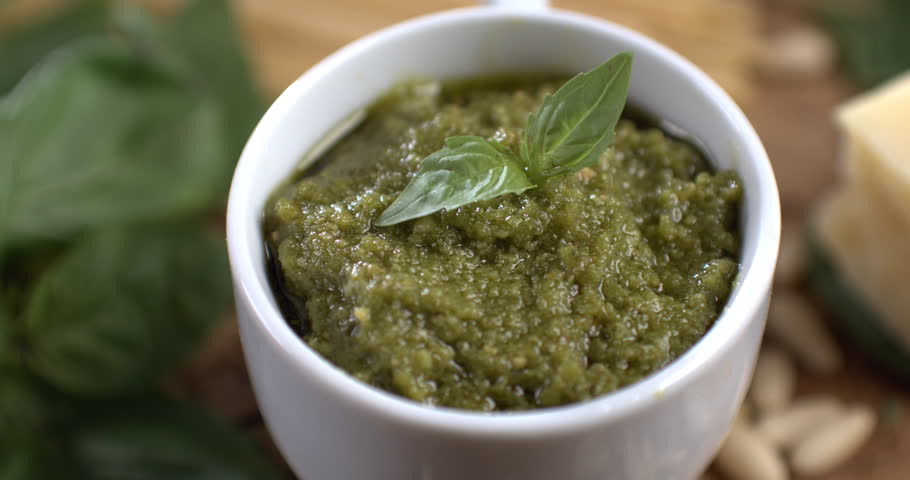 Pesto sauce. Genovese pesto, typical Italian gourmet sauce. Preparation of  green sauce in the typical old tradition marble mortar with basil leaves, pine nuts, olive oil, Parmesan cheese and salt.