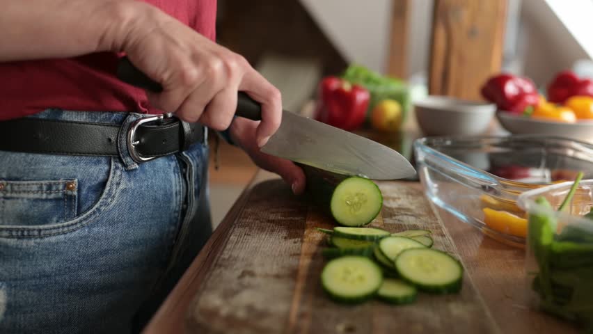 woman cutting cucumbers on a cutting board for healthy vegetable dinner Royalty-Free Stock Footage #1110919865