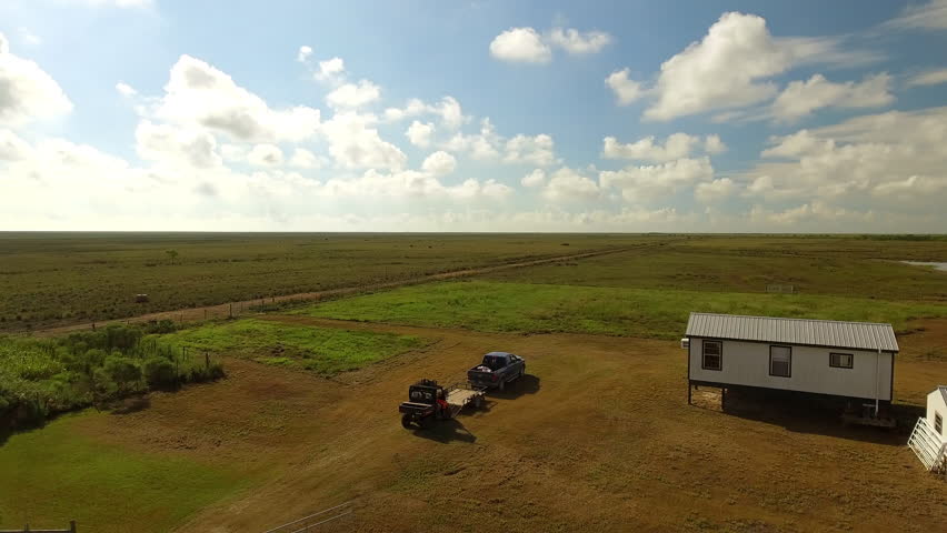 Aerial Panning Shot Of Vehicles Near House On Meadow Against Sky During Sunny Day - Bayou, Louisiana