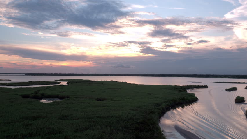 Aerial: Panning Idyllic Shot Of Rippled Sea Under Clouds, Drone Flying Backwards Over Landscape During Sunset - Bayou, Louisiana