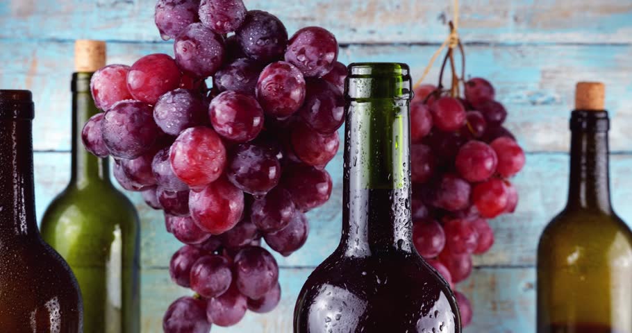 Pink grapes and wine bottles on a blue vintage wooden background.