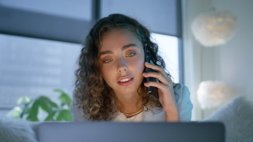 Portrait of small business owner working on laptop and speaking to client on phone in modern design interior. Young adult female baby face and amazing unique light blue color of eyes looking at laptop Royalty-Free Stock Footage #1110936095