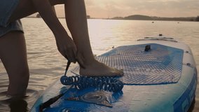 Close up of man puts safety rope on leg before SUP boarding. Male preparation for paddle boarding and water sports. Active and safety healthy lifestyle - Powered by Shutterstock - Get 15% off with code: PIKWIZARD15
