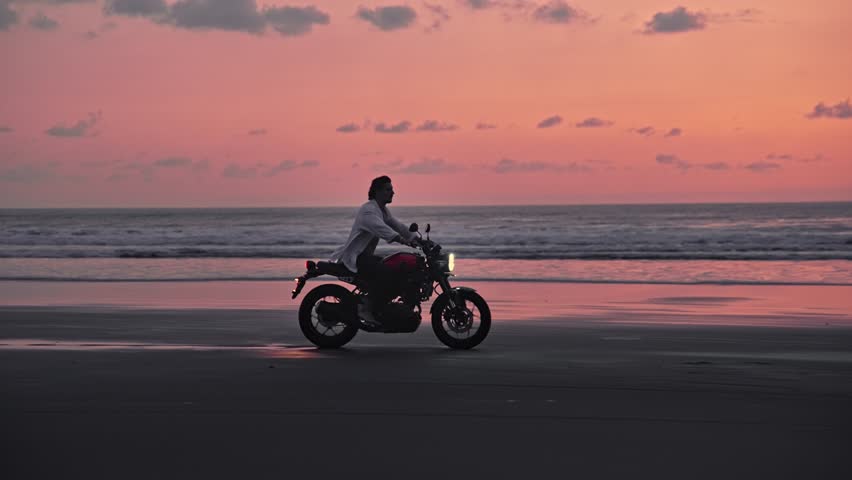 Person Riding Bike in Summer Landscape of Beach Traveling in Outdoors Nature. Handsome Motorcyclist or Surfer Driving Motorcycle in Speed Shot. Lifestyle of Alone Man in Motion on Stylish Transport