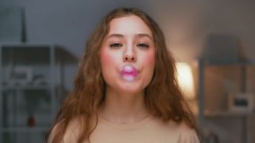 Portrait of Young Woman Chewing Gum and Blowing Colorful Bubble as Looking at Camera. Female Human in Living Room Shows Trick with Bubblegum Ball. Real Person Have Fun Playing with Pink Fruity Balloon - Powered by Shutterstock - Get 15% off with code: PIKWIZARD15