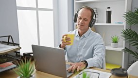 Cheerful middle age man, a successful executive, joyfully working at his office desk, listening to music and sipping his morning espresso coffee, brightening up the indoor workplace. - Powered by Shutterstock - Get 15% off with code: PIKWIZARD15