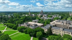 University of Notre Dame campus on beautiful summer day. Aerial descending shot above green lawn with Basilica of the Sacred Heart steeple and Main building golden dome. - Powered by Shutterstock - Get 15% off with code: PIKWIZARD15