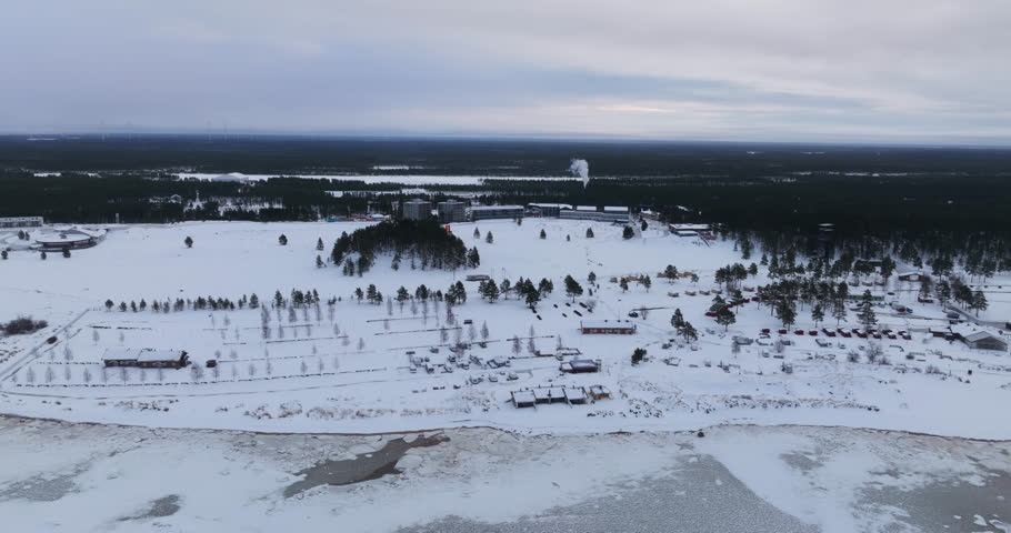 Aerial tracking shot overlooking the snowy coast of Kalajoen hiekkasarkat, winter in Finland