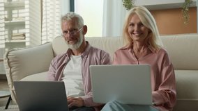Happy Caucasian elderly married couple senior man woman retired businesspeople business work on Internet together in living room using laptops smiling looking camera older people and modern technology - Powered by Shutterstock - Get 15% off with code: PIKWIZARD15