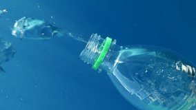 Vertical video, Plastic bottle flowing last bubbles of air and it sinks into blue deep in brightly sun rays, Mediterranean Sea, Slow motion. Plastic pollution of the Ocean