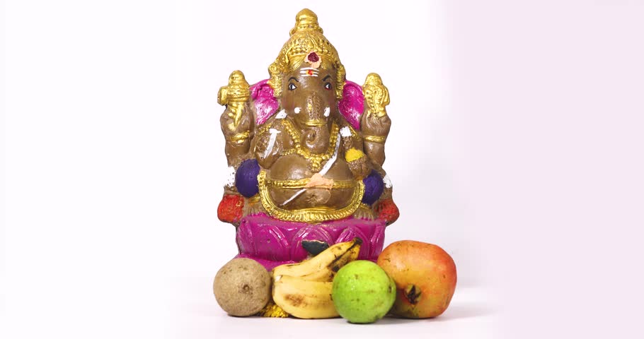 Ganesha Chaturthi festival is celebrated with Ganesha sculpture of Hindu god Ganesha and fruits on white background by sprinkling flowers on Ganesha sculpture. Royalty-Free Stock Footage #1110972881