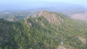 Aerial view of rock mountain with rock spikes on the summit. Nglanggeran prehistoric volcano landscape with forest vegetation. 4K drone shot - Yogyakarta, Indonesia